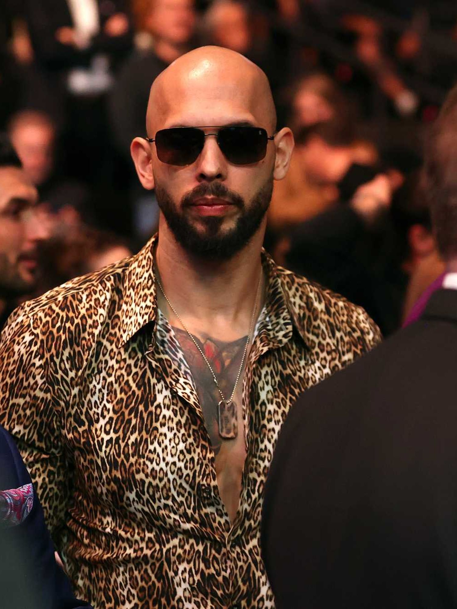 Andrew Tate in sunglasses and a leopard-print shirt at a UFC event.