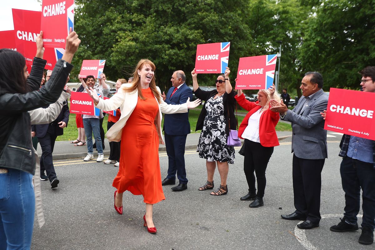 Angela Rayner wears an orange dress as she parades through a group of people holding 'change' signs