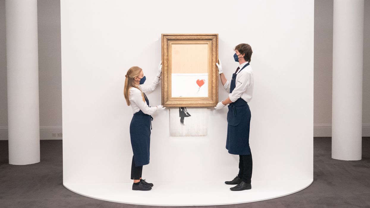 Art handlers at Sotheby’s auction house with Banksy’s Love Is In The Bin, which self-shredded immediately after it was sold at auction (Dominic Lipinski/PA)