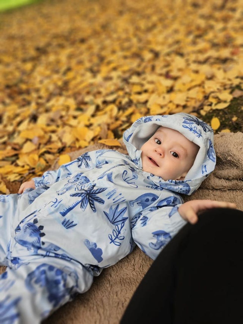 Arthur Ransom lying down and wearing a baby grow with a hoodie