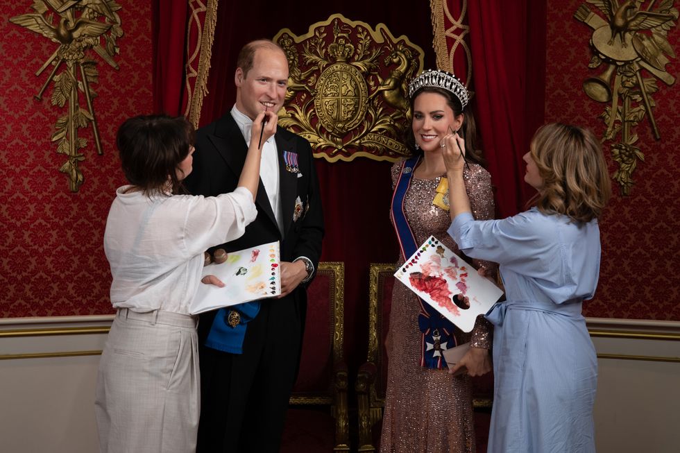 Artists brushing paint on wax figures of Kate and William