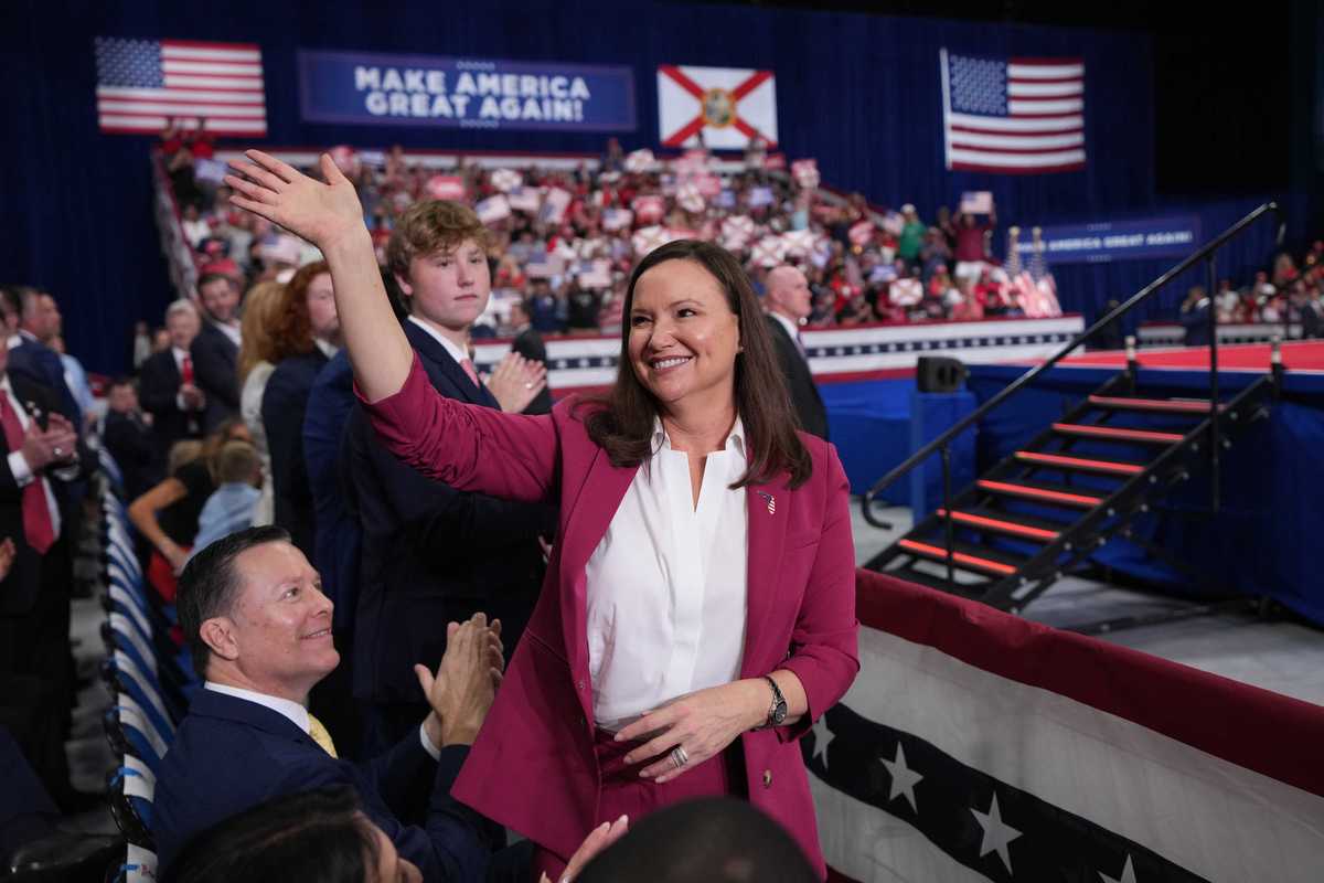 Ashley Moody, a white woman with long brown hair, smiles and waves at the crowd at a rally in Florida.