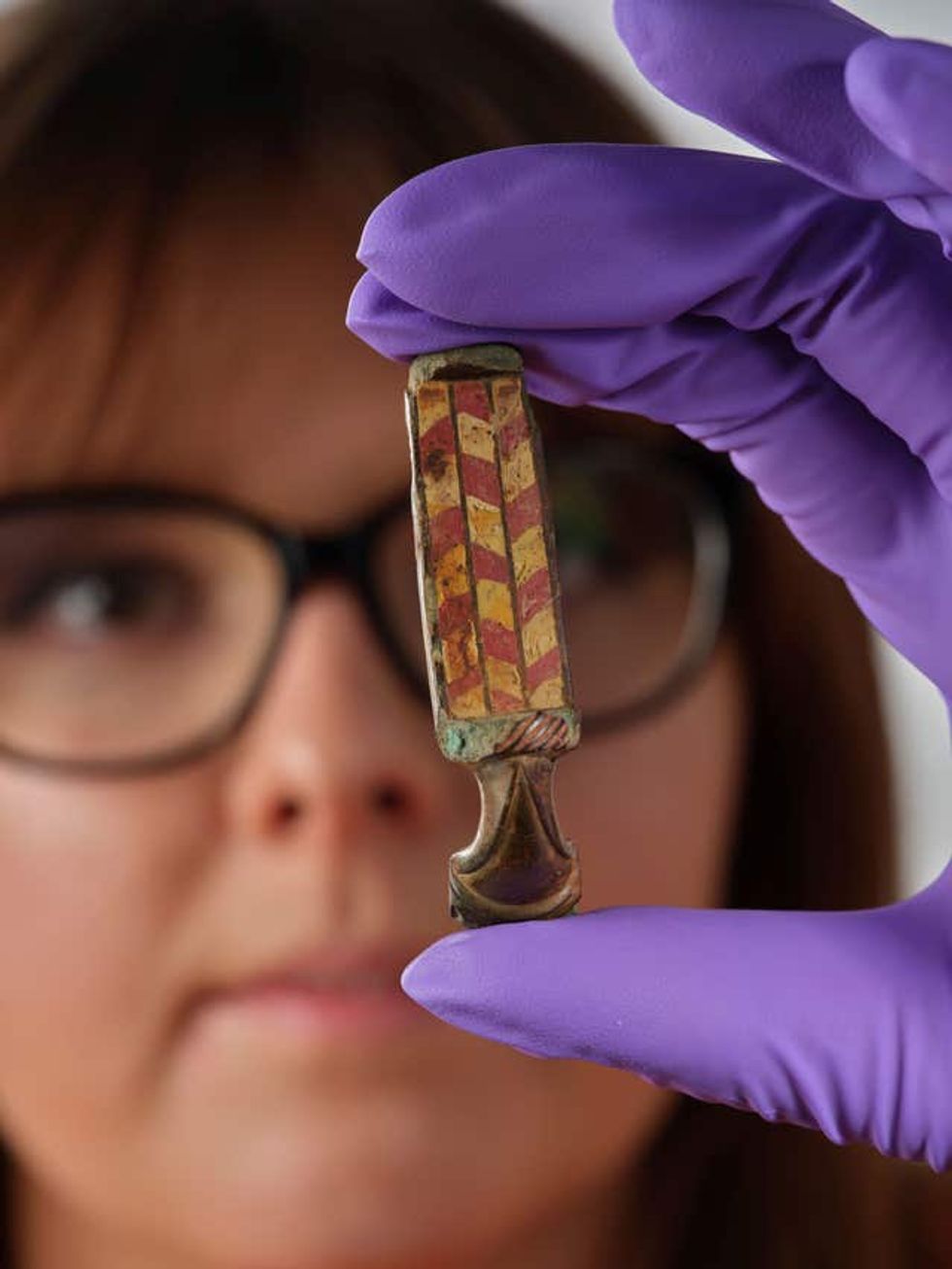 Assistant curator Bethany Simpson holding a Roman brooch