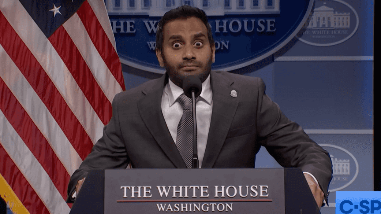 Aziz Ansari as Kash Patel on Saturday Night Live, staring with bulging eyes behind a White House lectern.
