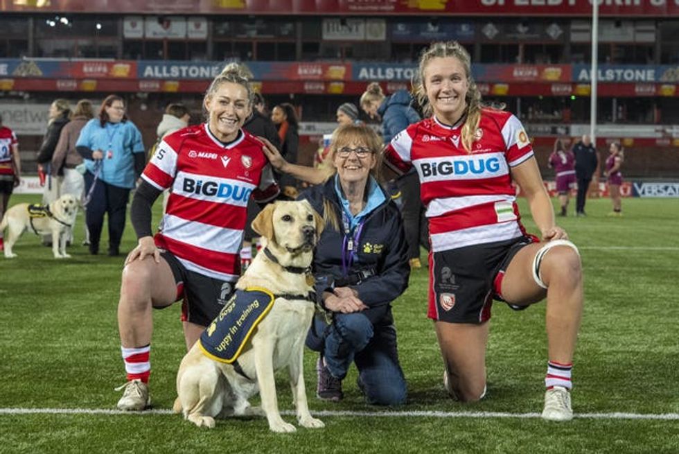 Bailey, an 18-month-old Labrador, with volunteer puppy raiser Davarin Tennant and Gloucester Hartpury players Mo Hunt, (left) and Zoe Aldcroft, (right) at Kingsholm Stadium in Gloucester