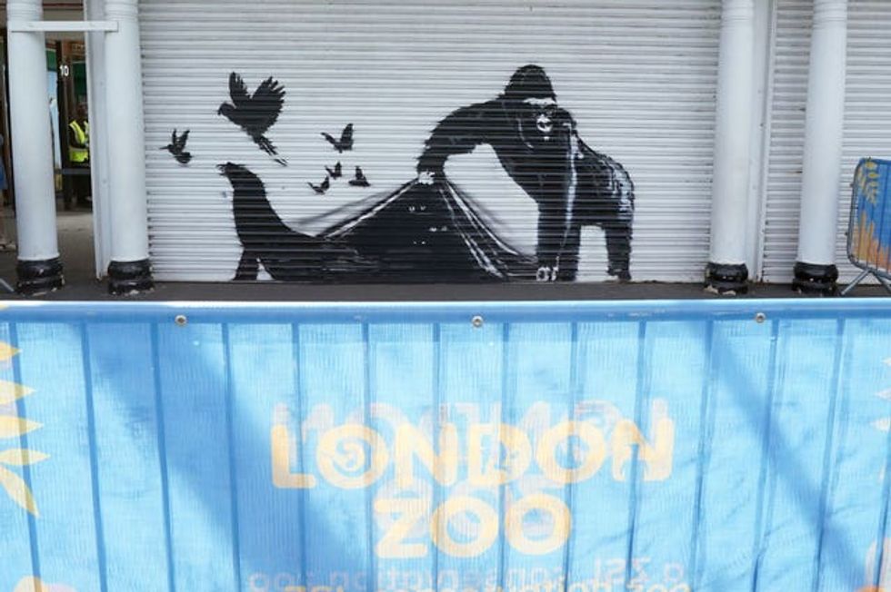 Banksy artwork of a gorilla lifting the edge of a shutter at the entrance to London Zoo