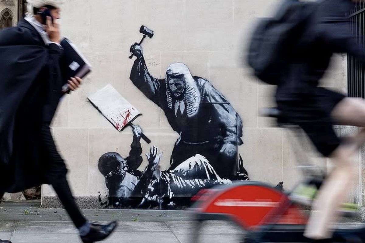 Banksy artwork on a wall depicting a judge attacking a protester with a white placard.