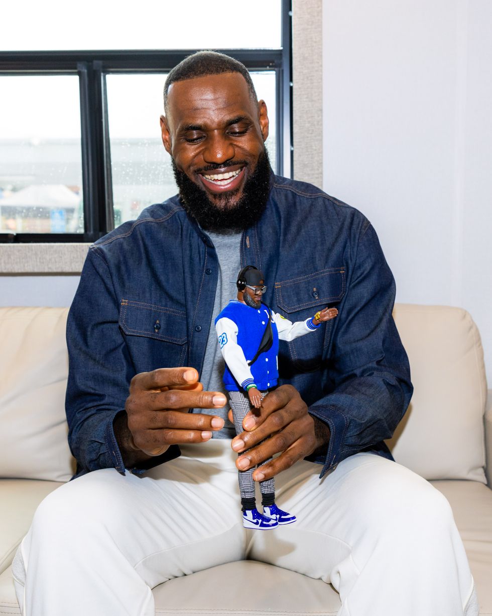 Basketball player LeBron James smiling and playing with a Ken doll made in his likeness