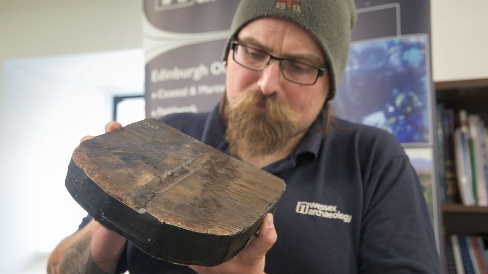 Ben Saunders, senior marine archaeologist at Wessex Archaeology, studies a timber sample