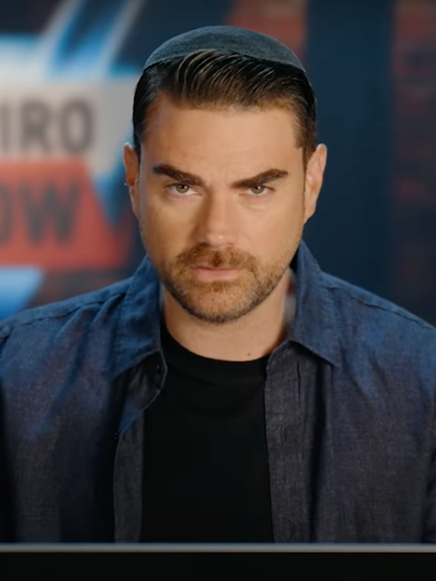 Ben Shapiro talking to the camera in his studio as he presents The Ben Shapiro Show.