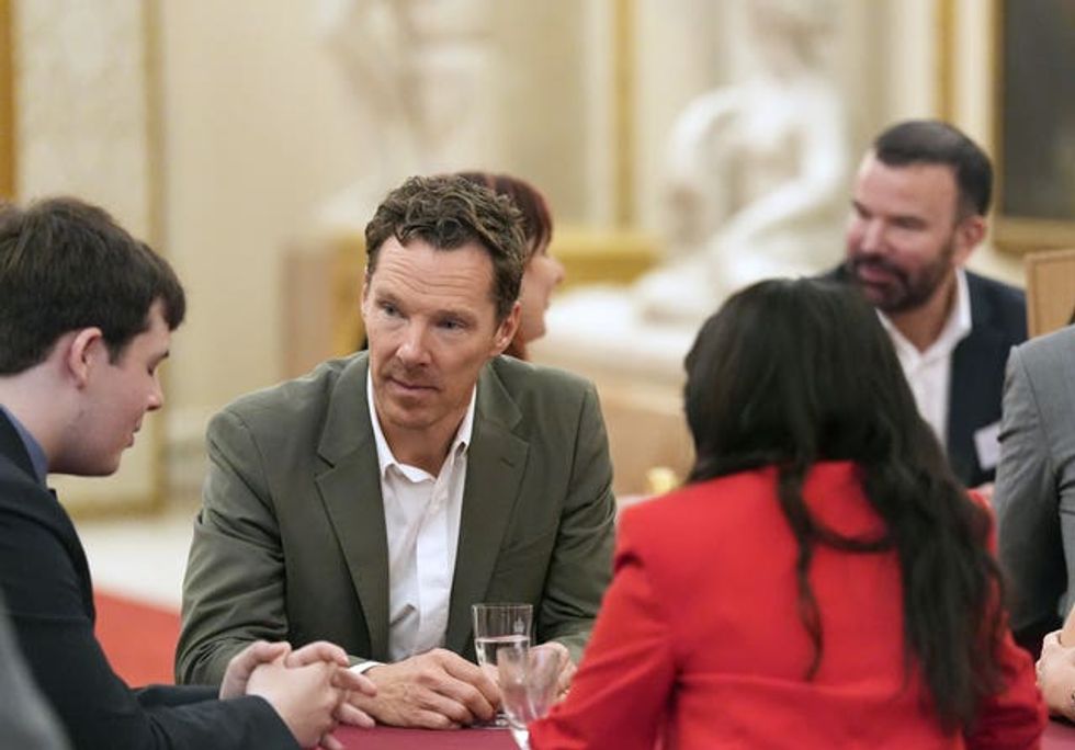 Benedict Cumberbatch speaking with people seated at a table