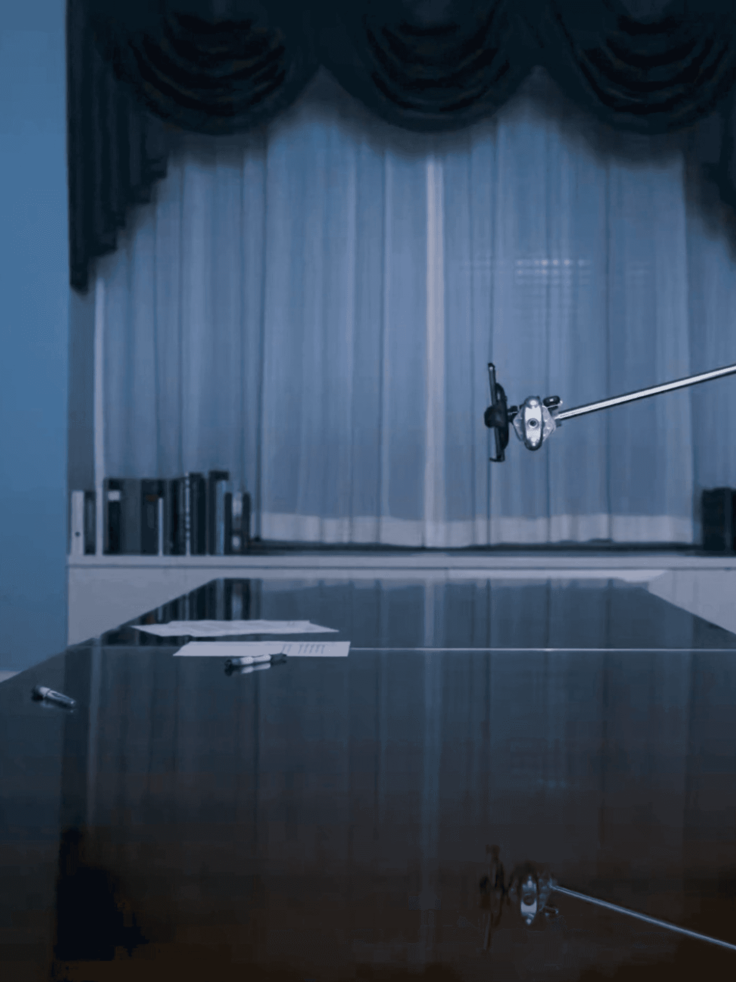 Bernie Sanders, left, a white man with glasses, short white hair and a suit, sits at a table opposite an iPhone on a stand.