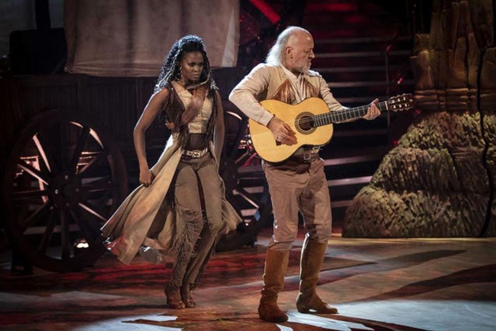Bill Bailey using a guitar as a prop during a safari-themed performance with Oti Mabuse