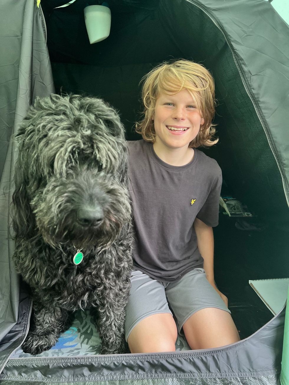 Billy sitting inside his tent with his dog