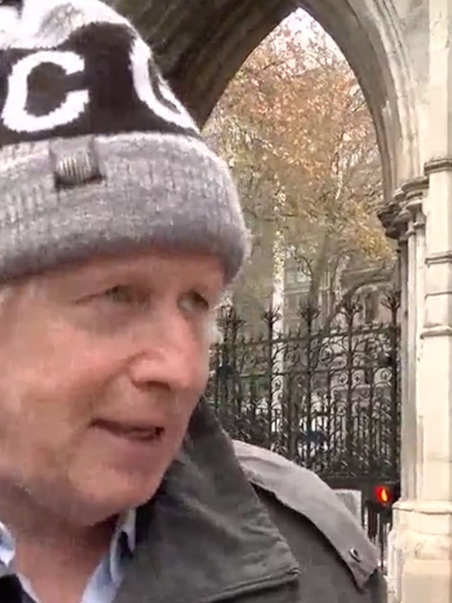 Boris Johnson, a white man with a grey beanie and grey coat, speaks to the media outside in London.