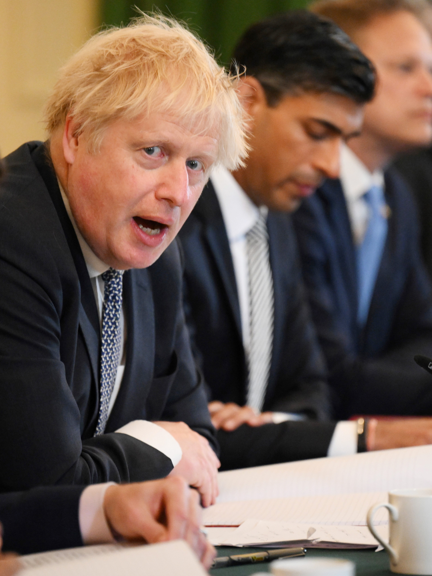 Boris Johnson and several other suited men around a green table, as he hosts a Cabinet meeting.