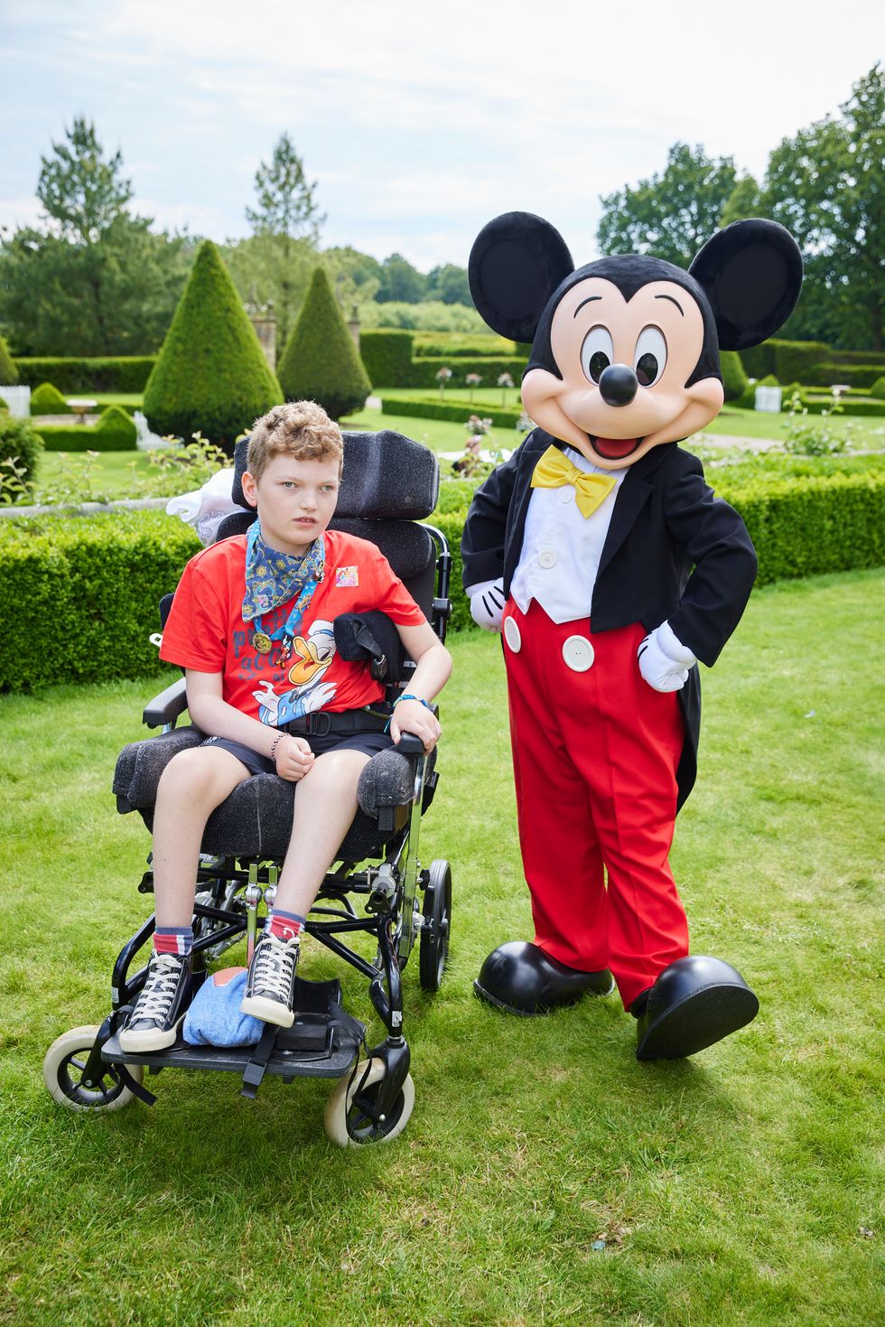 Boy in wheelchair next to man dressed as mouse