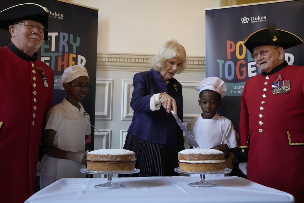 Camilla cuts a Victoria sponge cake for which she had shared her personal recipe for Poetry Together tea parties (Frank Augstein/PA)
