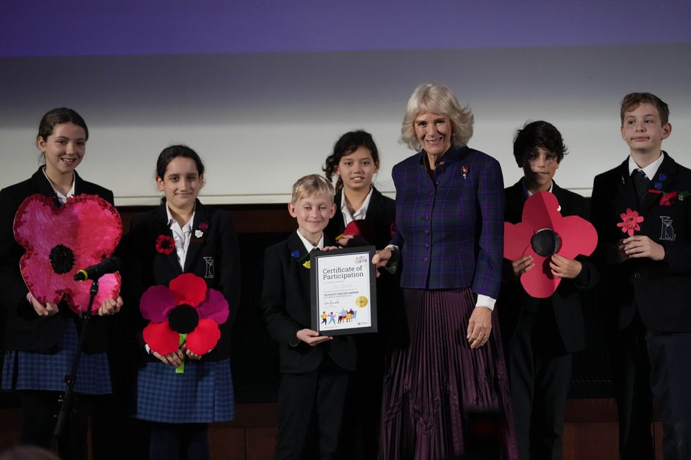 Camilla hands a certificate to pupils from London\u2019s Lyceum school who recited Why Wear A Poppy? by Donald Crawford (Frank Augstein/PA)