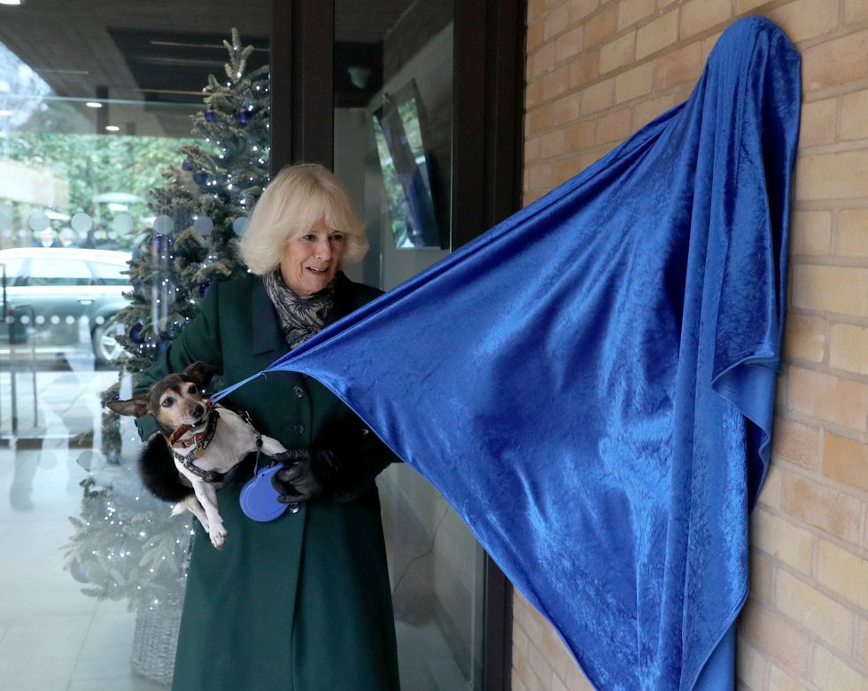 Camilla with Beth unveiling a plaque with the help of a sausage (Steve Parsons/PA)