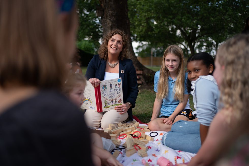 Captain Sir Tom Moore\u2019s daughter Hannah Ingram-Moore reads to children who feature in One Hundred Reasons to Hope. (Joe Giddens/ PA)