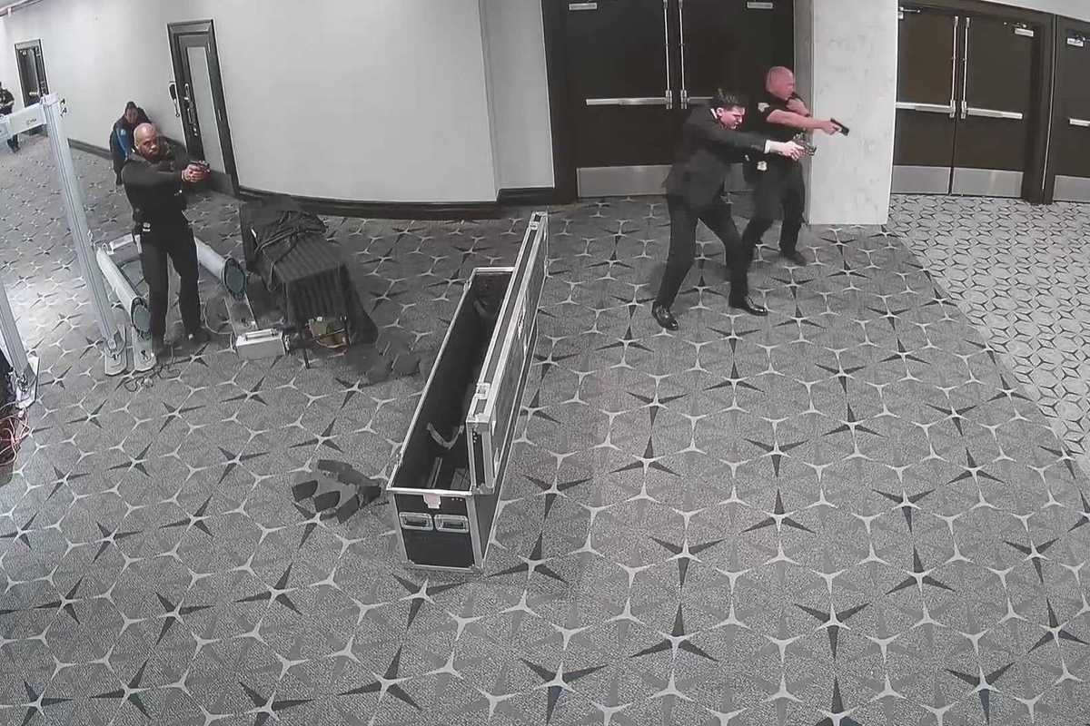 CCTV footage of federal agents pointing their guns at someone off-camera in a hotel lobby.