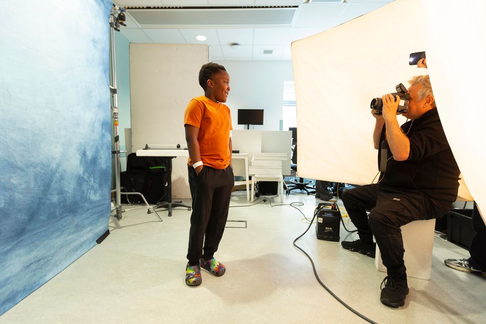 Celebrity photographer Rankin taking an image of a young boy dressed in a orange T-shirt
