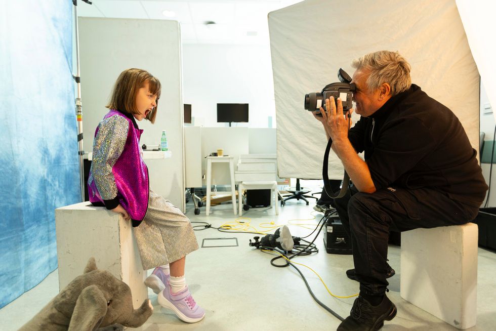 Celebrity photographer Rankin taking an image of a young girl sat on a box draped in a white sheet