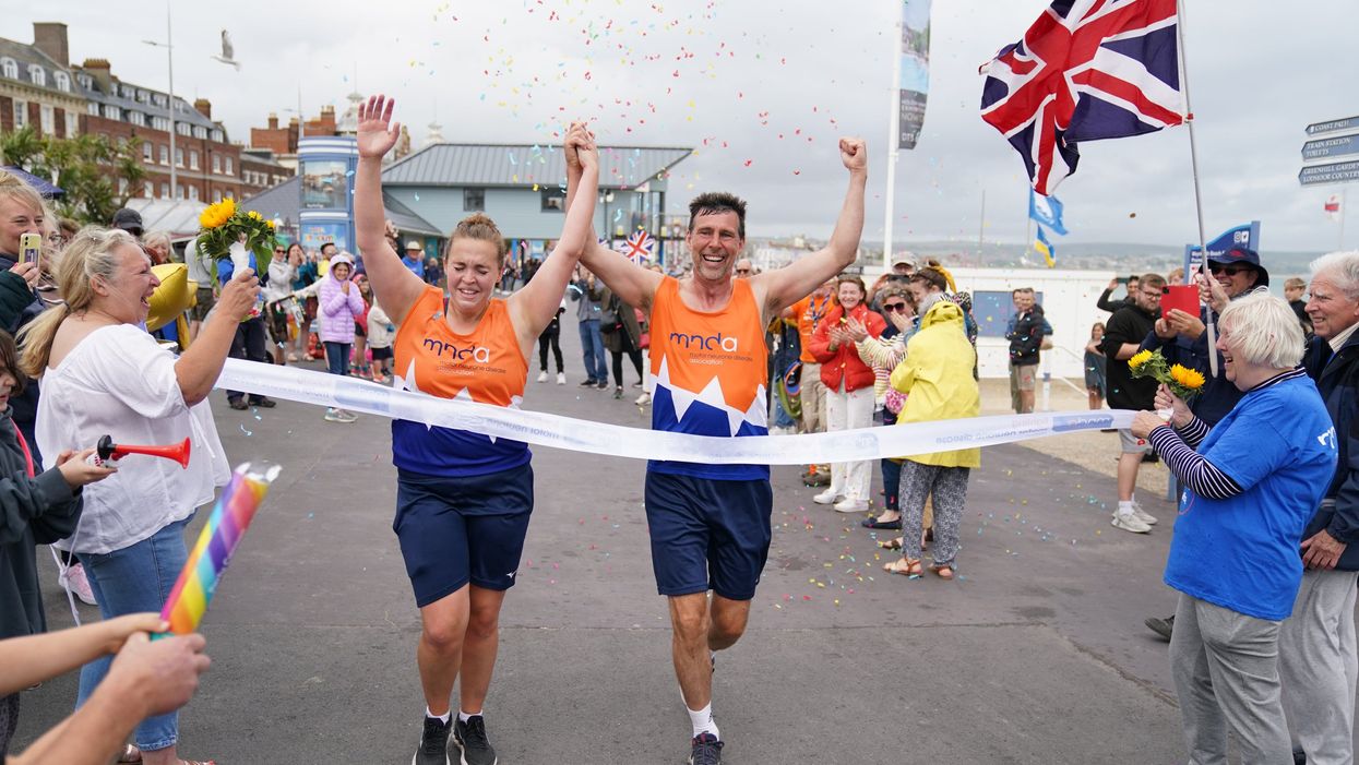 Charlotte Nichols and Stuart Bates finishing their marathon at Weymouth Beach (Andrew Matthews/PA)