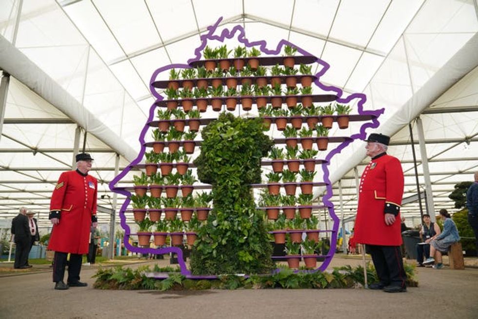 Chelsea Pensioners Ted Fell, left, and George Reid pose beside florist Simon Lycett\u2019s The Queen\u2019s Platinum Jubilee, a purple metal display shaped like the profile of Queen Elizabeth II containing 70 hand-thrown terracotta pots, one for each year of the Queen\u2019s reign, and each planted with a Lily of the Valley, during the RHS Chelsea Flower Show press day at the Royal Hospital Chelsea, London