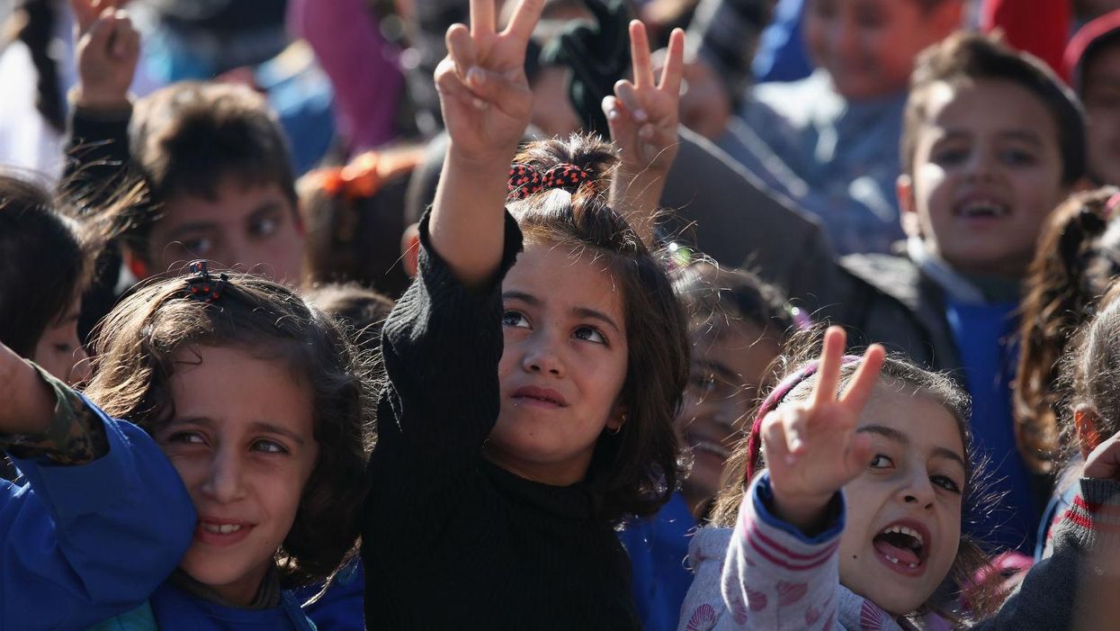 Children flash the victory sign after singing the Rojava anthem at a public elementary school on November 12, 2015 in Qamishli, Rojava, Syria