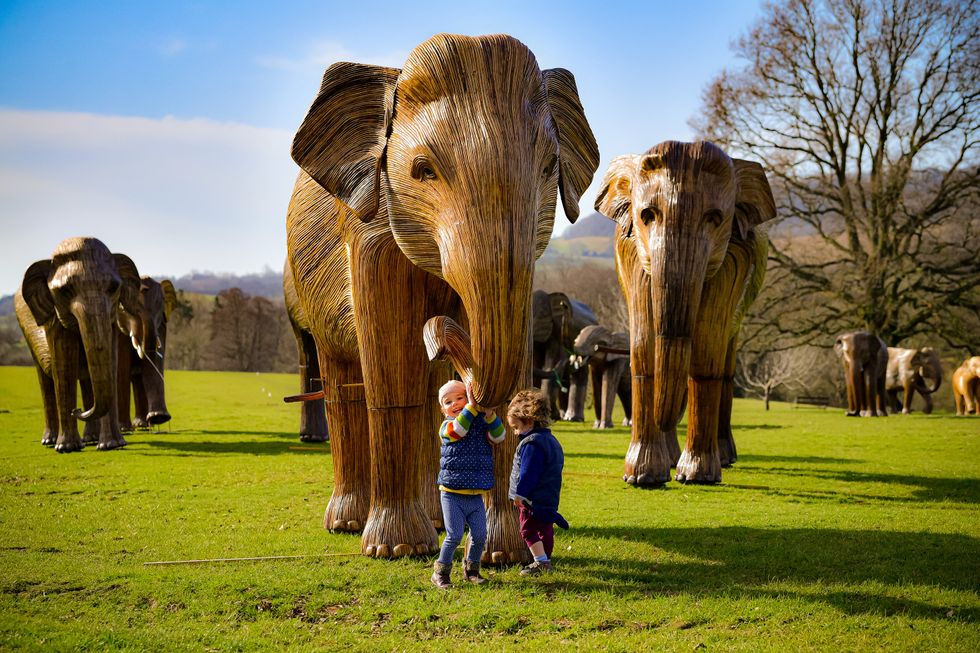 Children (names not given) play around a herd of life-size elephant figures created by international conservation charity Elephant Family on display at Sudeley Castle in Winchcombe, Gloucestershire