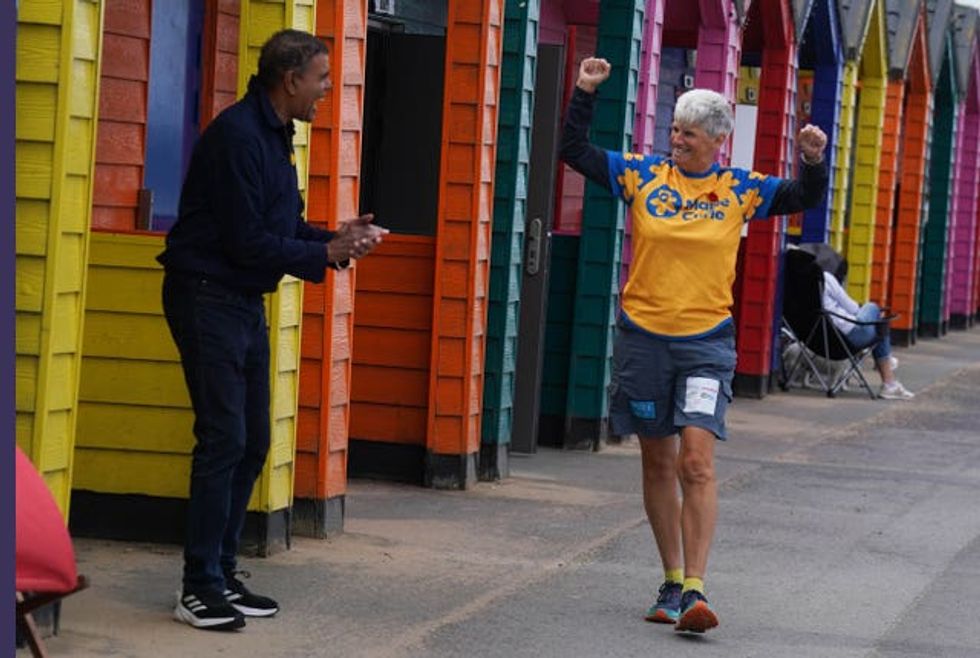Chris Kamara claps as Tracey Howe walks past colourful beach huts