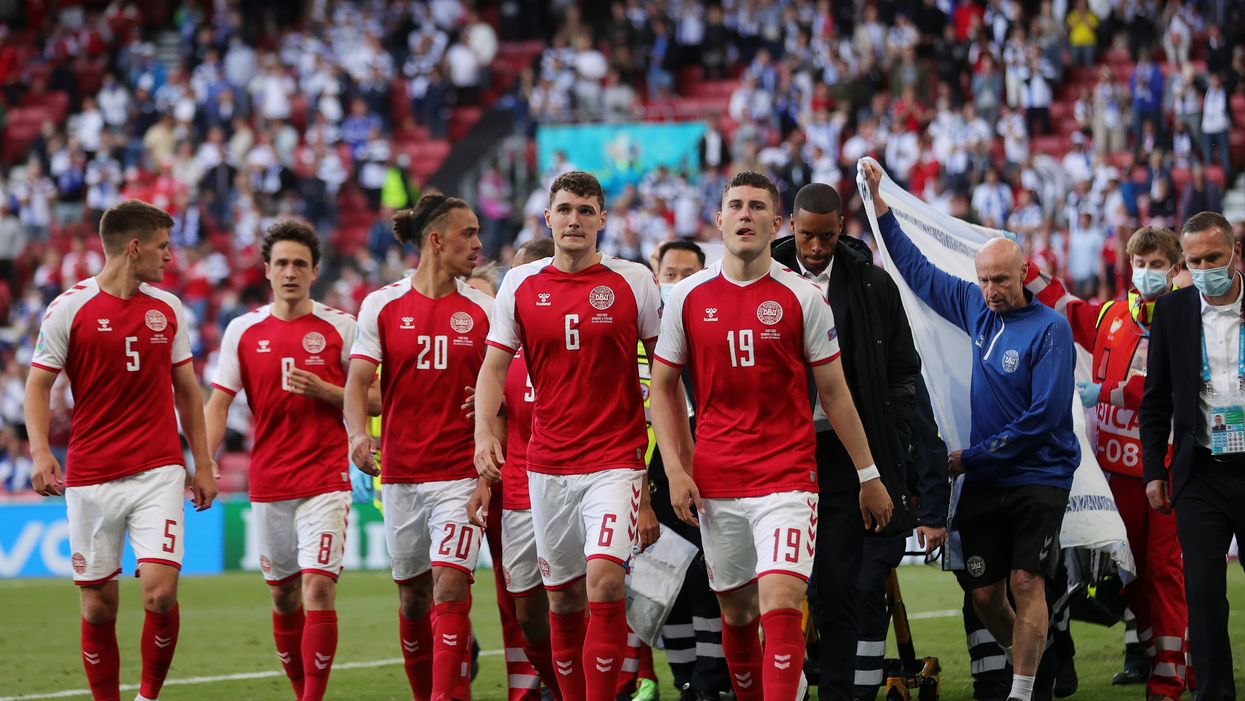 <p>Christian Eriksen is escorted off of the field by team mates and medics on a stretcher</p>
