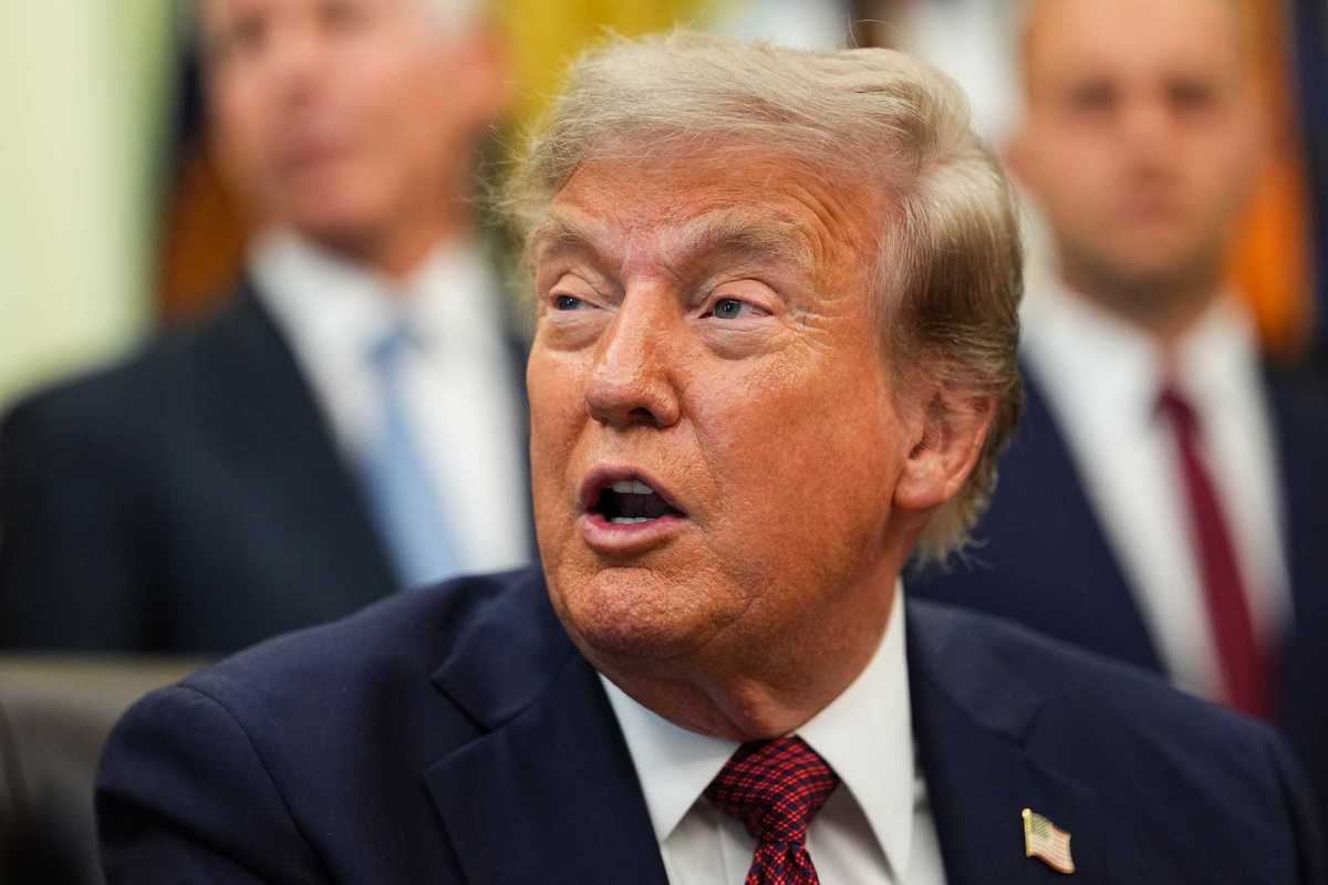 Close-up of Donald Trump looking to his right and speaking to reporters in the Oval Office.