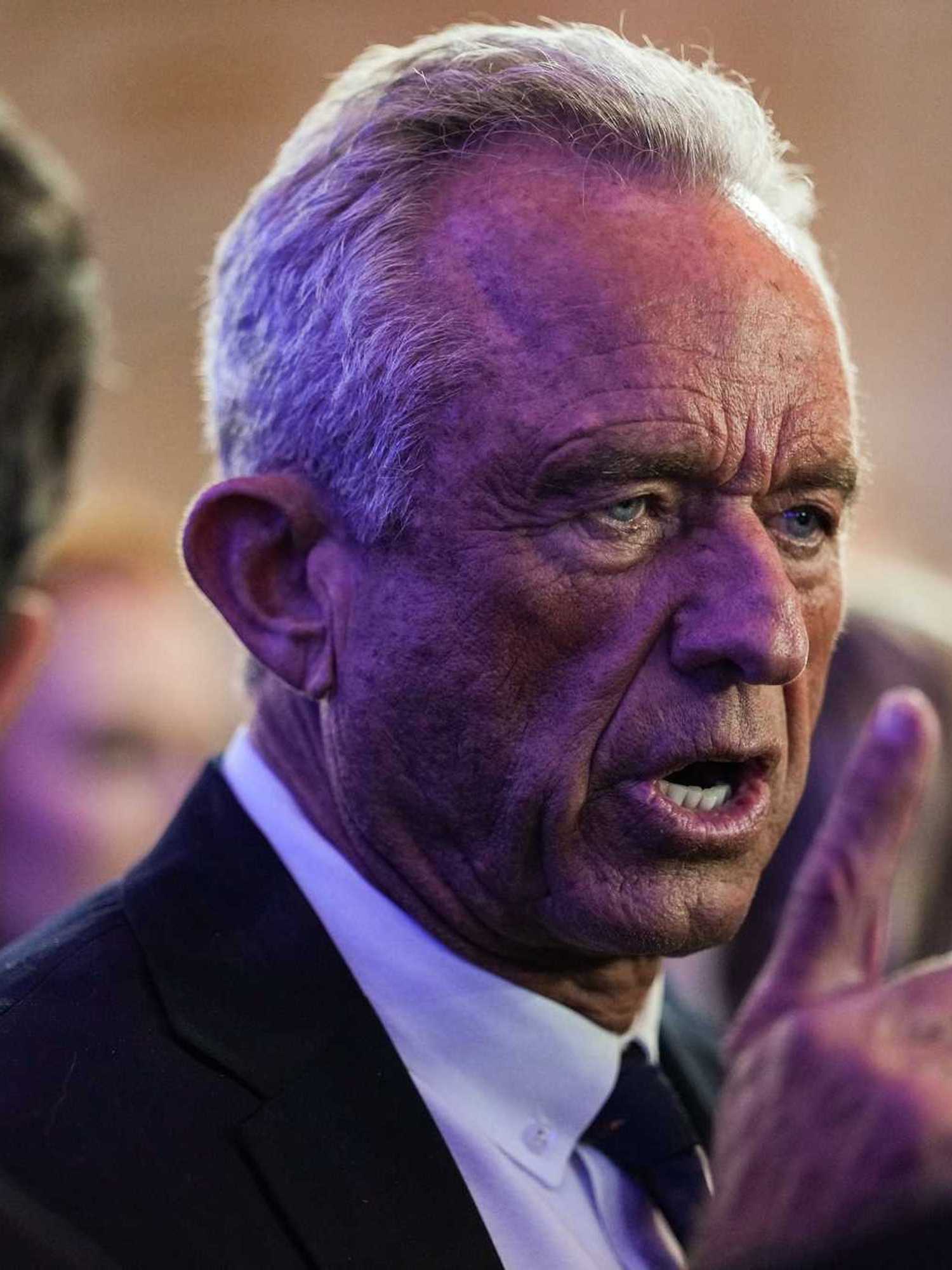 Close up of Robert F. Kennedy Jr talking to people at the White House Correspondents' Dinner. He has his right index finger raised.