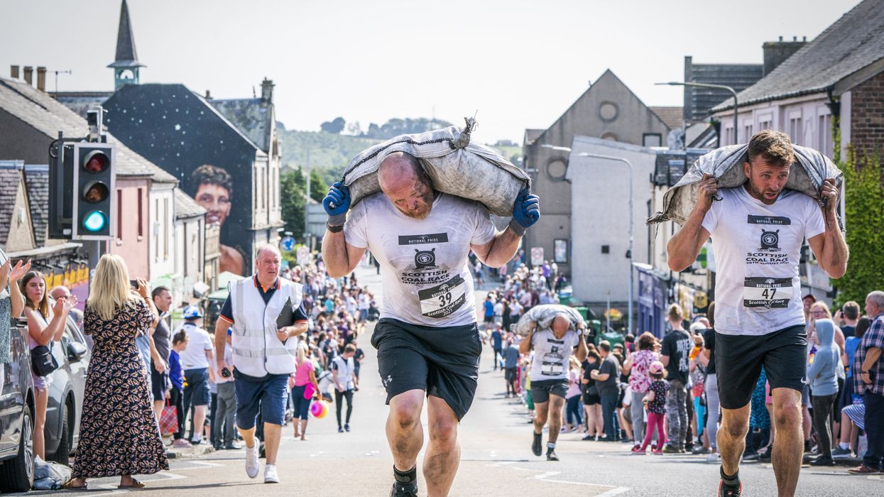 Competitors in the Scottish Coal Carrying Championships through the streets of Kelty in Fife (Jane BarlowPA)