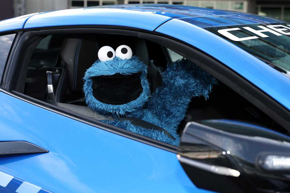 Cookie Monster, a blue puppet, inside a blue car.