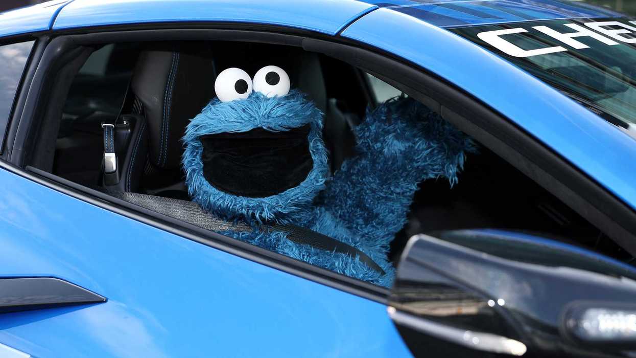 Cookie Monster, a blue puppet, inside a blue car.