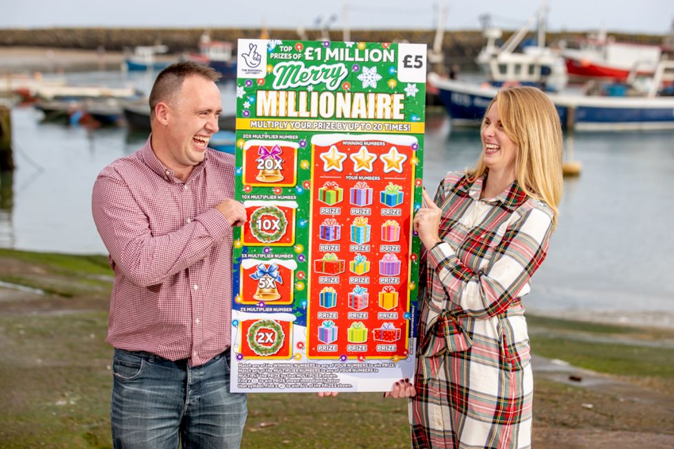 Couple hold a giant scratch card which they won \u00a31 million from