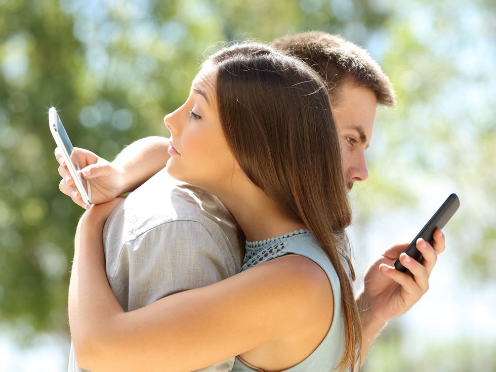 Couple of cheaters hugging and texting everyone on their smartphones