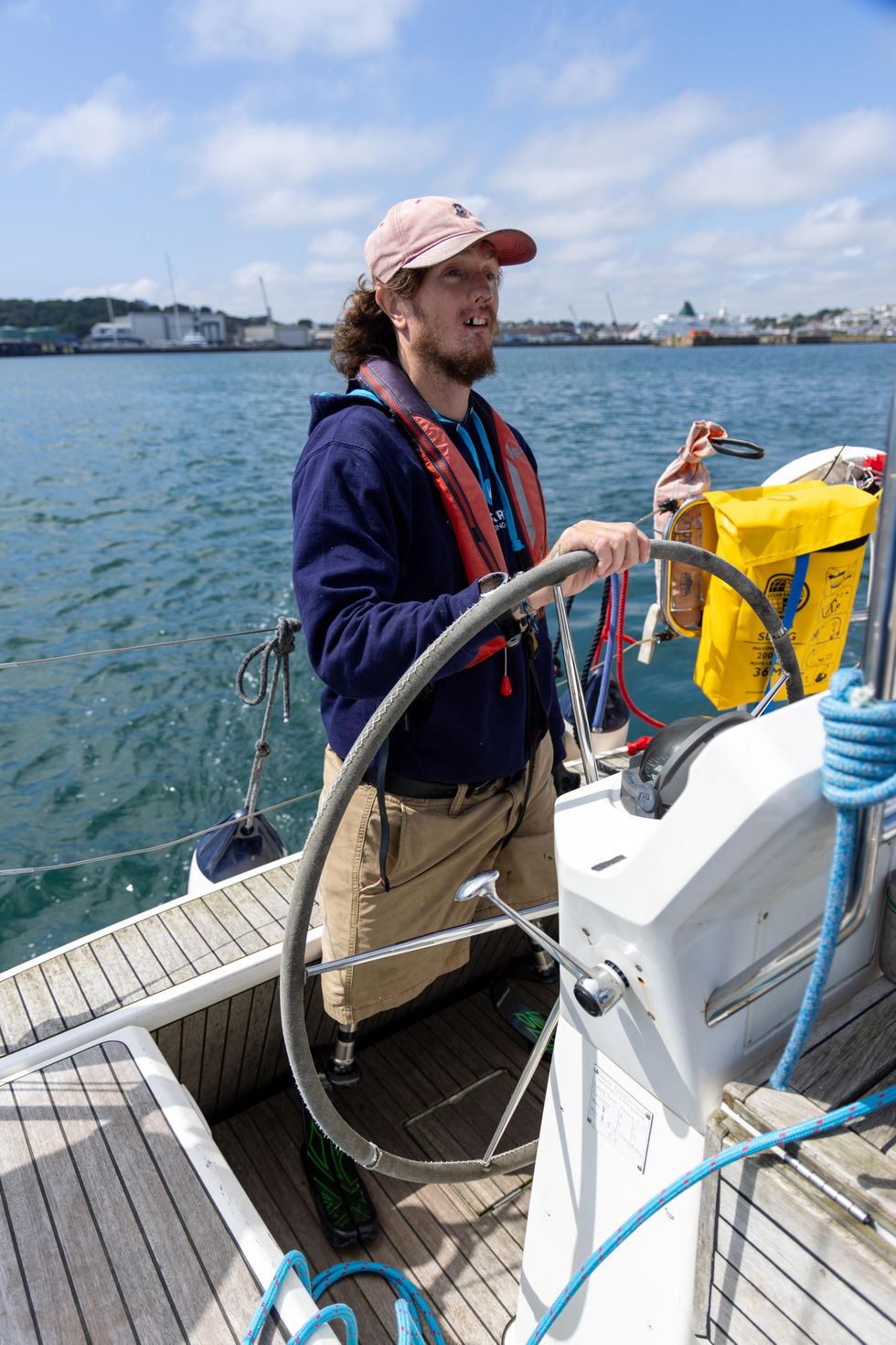 Craig Wood standing at the helm of his sailing boat holding the steering wheel