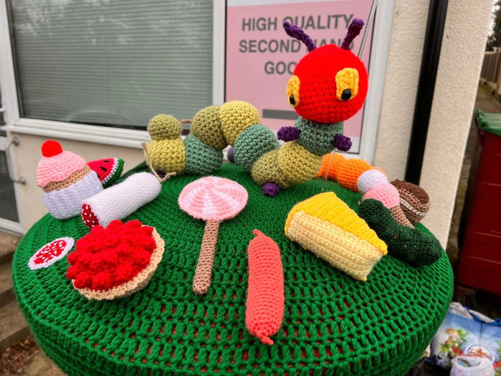 Crocheted caterpillar and food on top of postbox
