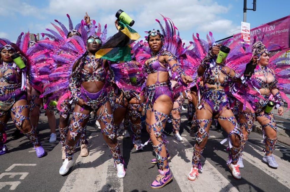 Dancers in colourful costumes preparing to take part in the Notting Hill Carnival