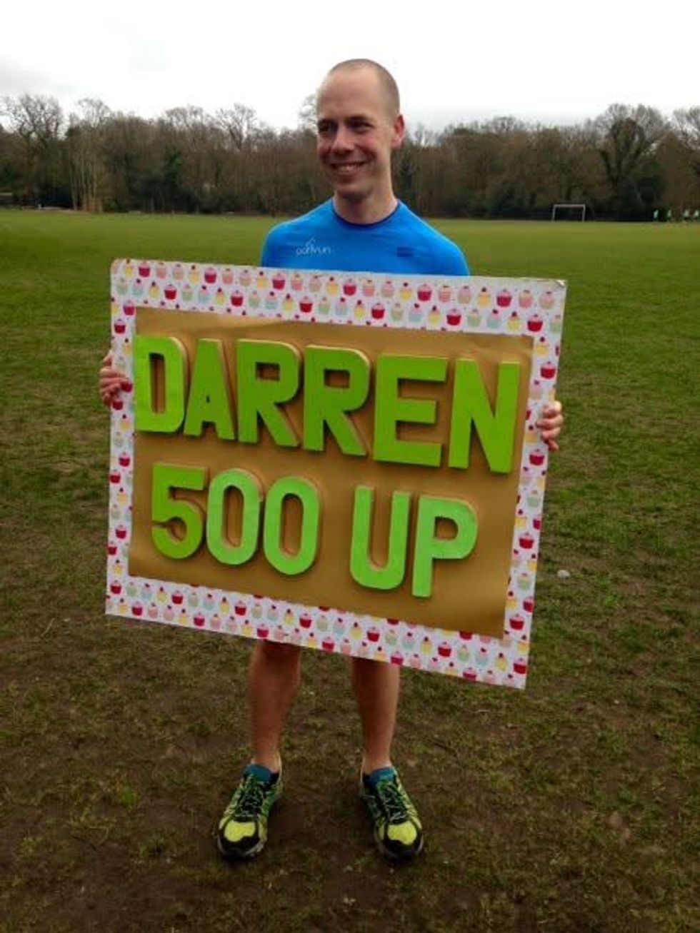 Darren Wood holding a sign saying 'Darren 500 up' to celebrate his 500th parkrun