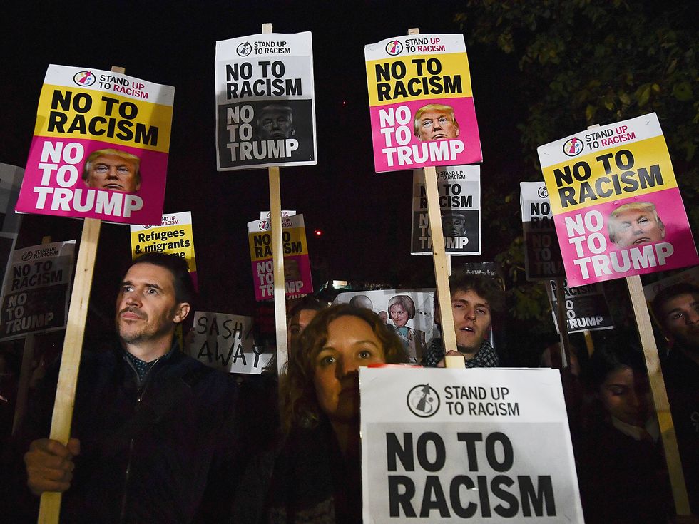 Demonstrators hold placards that read 'No to racism, no to Trump' during a protest outside the US Embassy in London