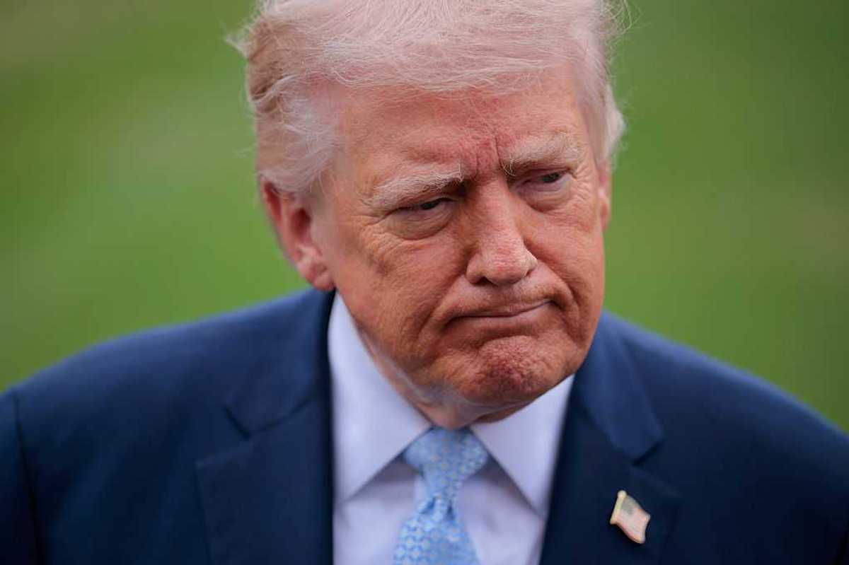 Donald Trump, a white man with short blonde hair and a blue suit, frowning slightly.