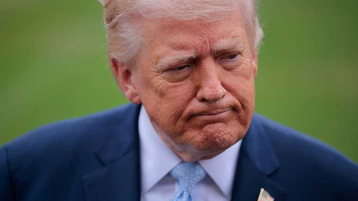 Donald Trump, a white man with short blonde hair and a blue suit, frowning slightly.