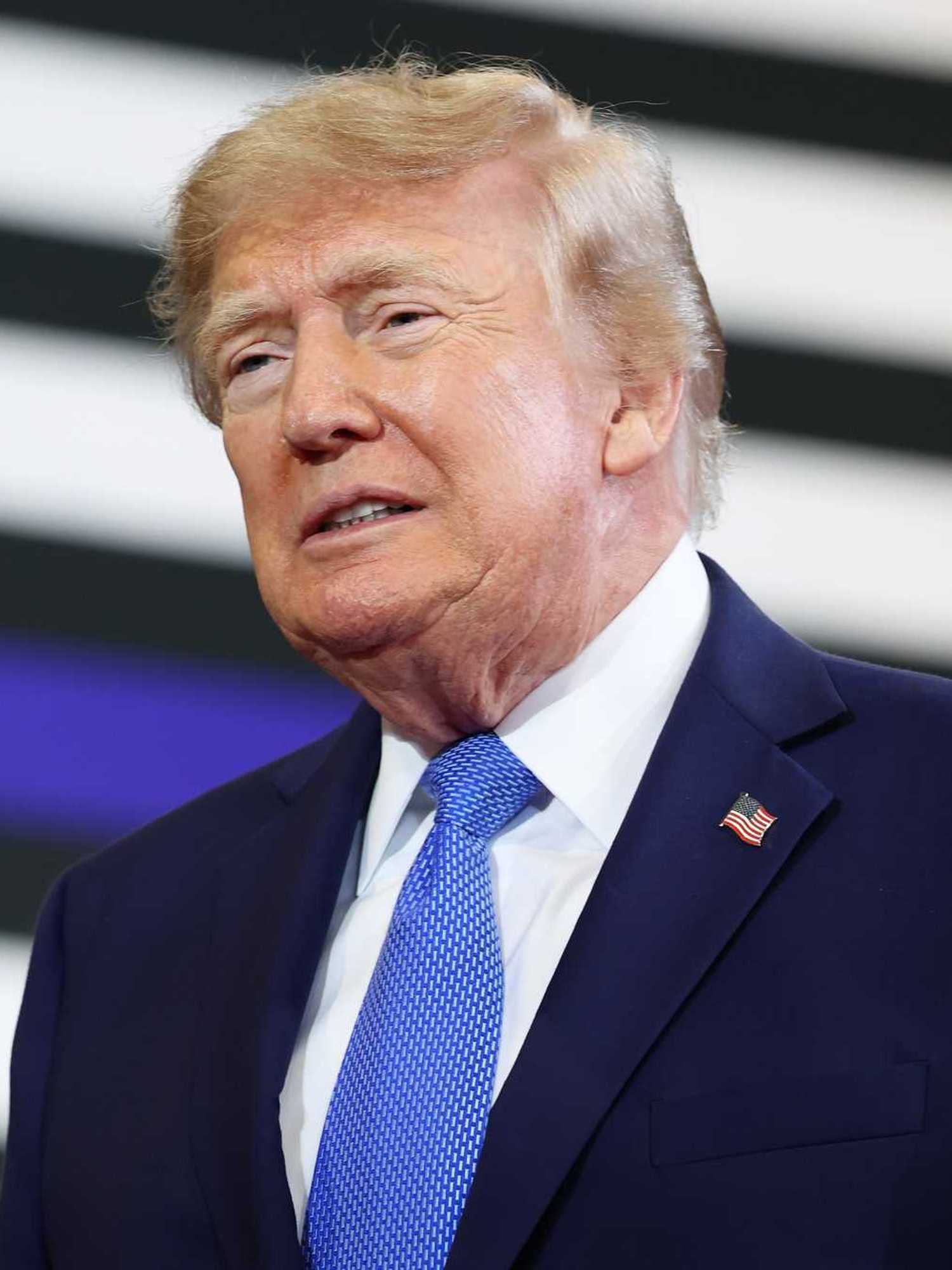 Donald Trump, a white man with short blonde hair and a navy suit.
