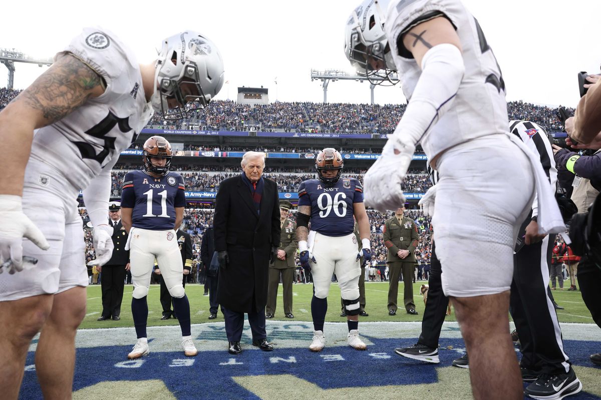 Donald Trump and American football players stare at the ground on the pitch after the US president tossed the coin to start the game.